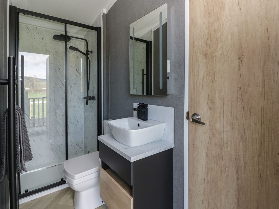 A bathroom with a shower, toilet, and sink at Dawn's Rest Nantmel near Rhayader