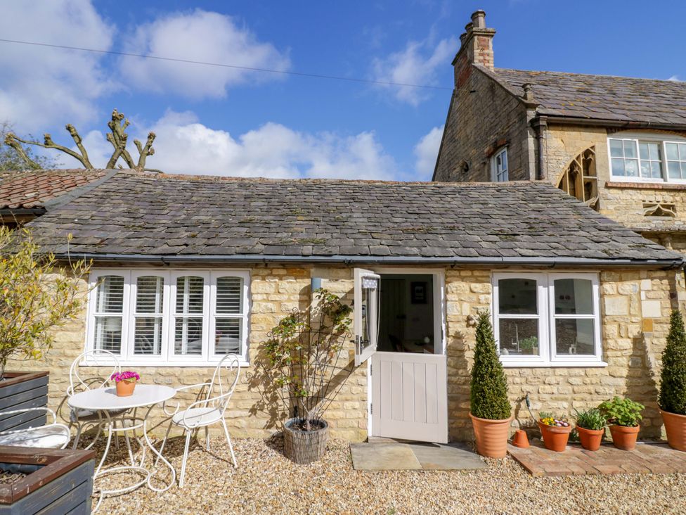 A cottage with tables and chairs in the outdoor area at Halliday’s Cottages - The Cottage, Greetham near Cottesmore