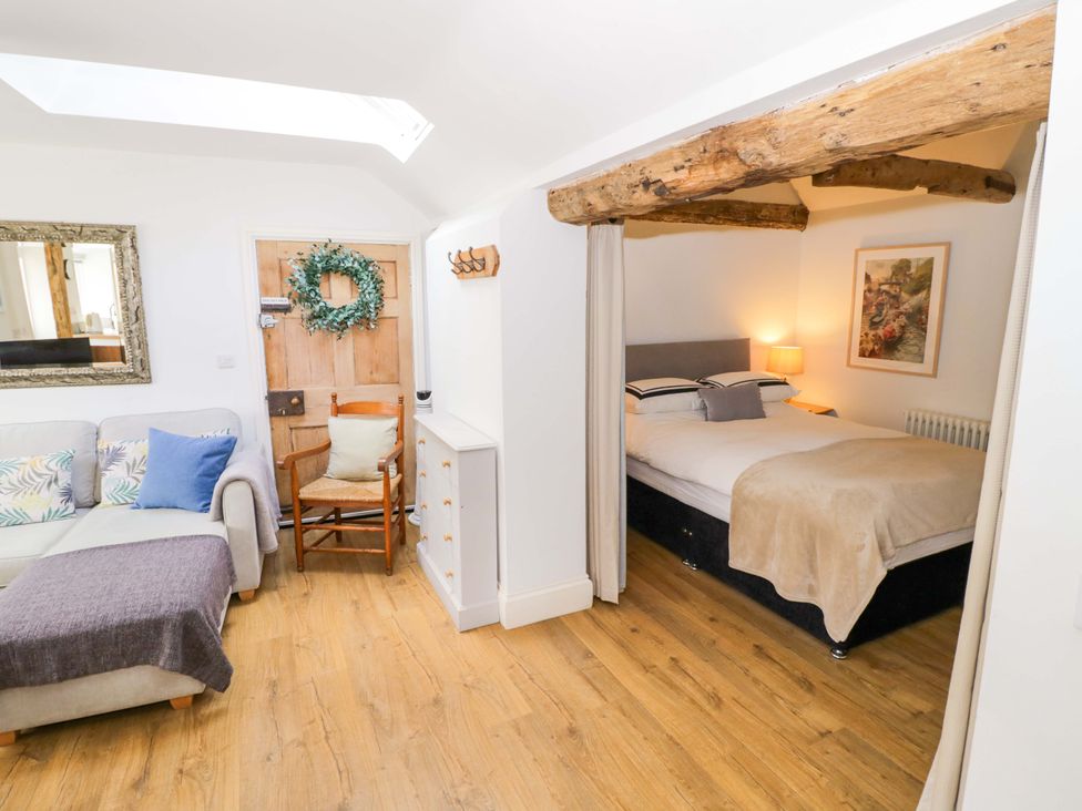 A living room with a bed and a chair at Halliday’s Cottages - The Cottage in Greetham near Cottesmore