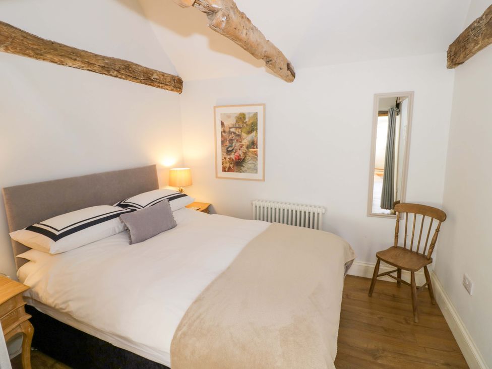 A bedroom with a bed, lamp, and chair at Halliday’s Cottages - The Cottage Greetham near Cottesmore