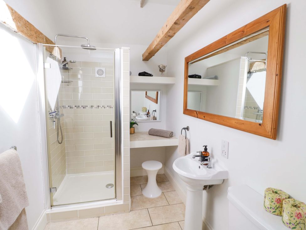 A bathroom with a shower, sink, and mirror at Halliday’s Cottages - The Cottage in Greetham near Cottesmore