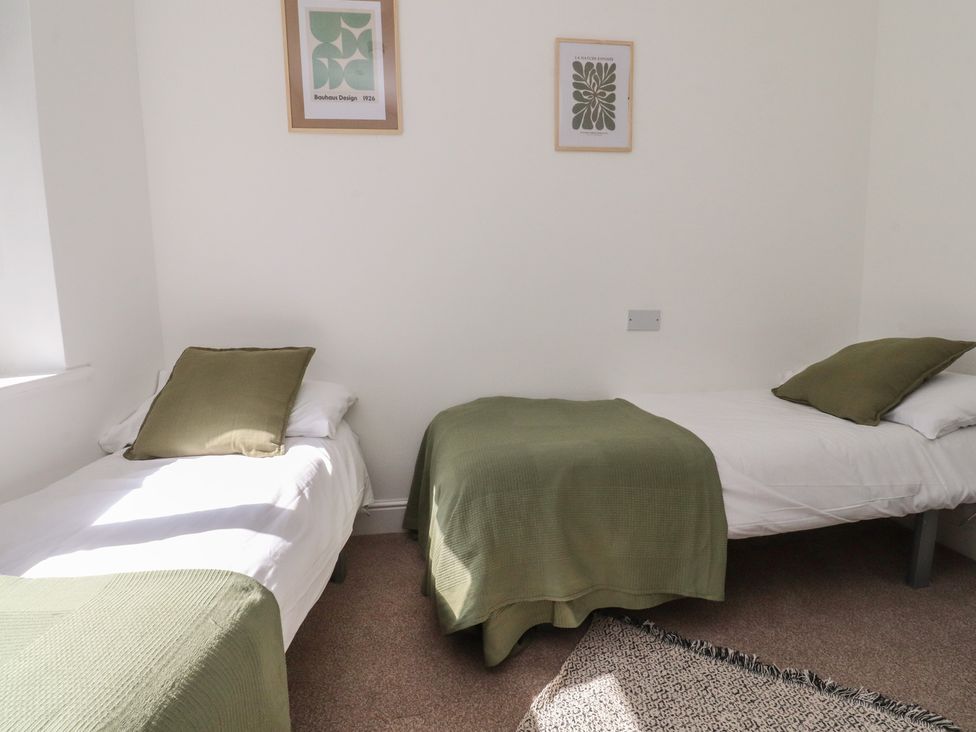 A bedroom with two beds and framed pictures at Beacon Fell Cottage 1 Preston