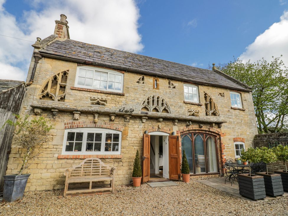 A house exterior with benches and planters at Halliday’s Cottages - The Folly Greetham near Cottesmore