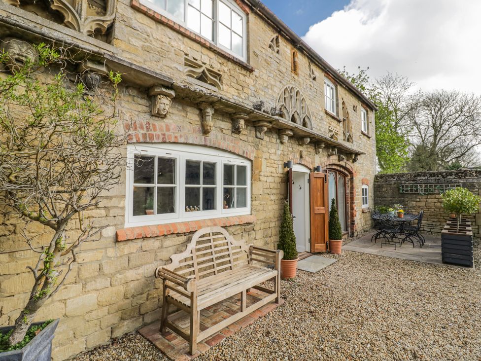 An outdoor area with a stone wall and a bench at Halliday’s Cottages - The Folly Greetham near Cottesmore