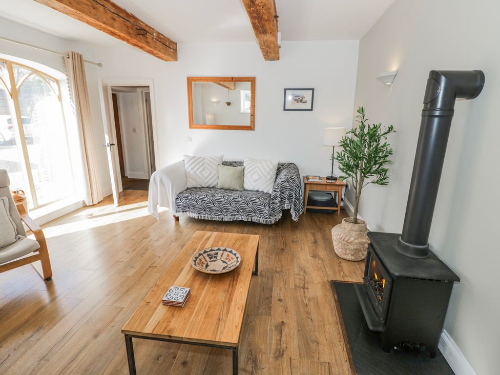 A living room with a sofa and wood stove at Halliday’s Cottages - The Folly near Greetham