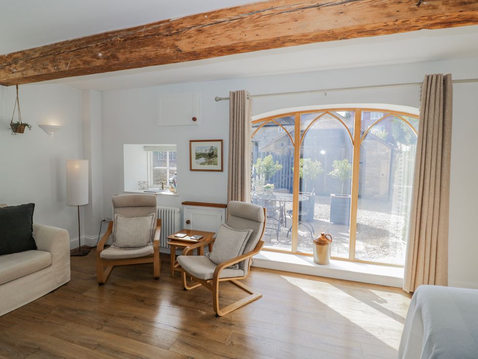 A living room with an armchair and a side table at Halliday’s Cottages - The Folly Greetham near Cottesmore