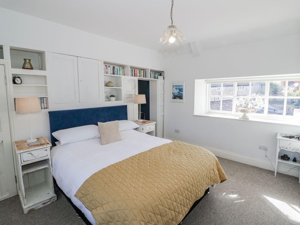 A bedroom with a bed, bookshelf and window at Halliday’s Cottages - The Folly in Greetham near Cottesmore