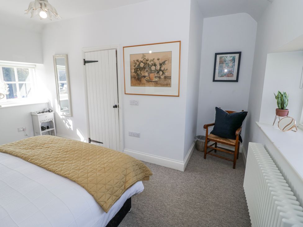A bedroom with a bed and a mirror at Halliday’s Cottages - The Folly in Greetham near Cottesmore