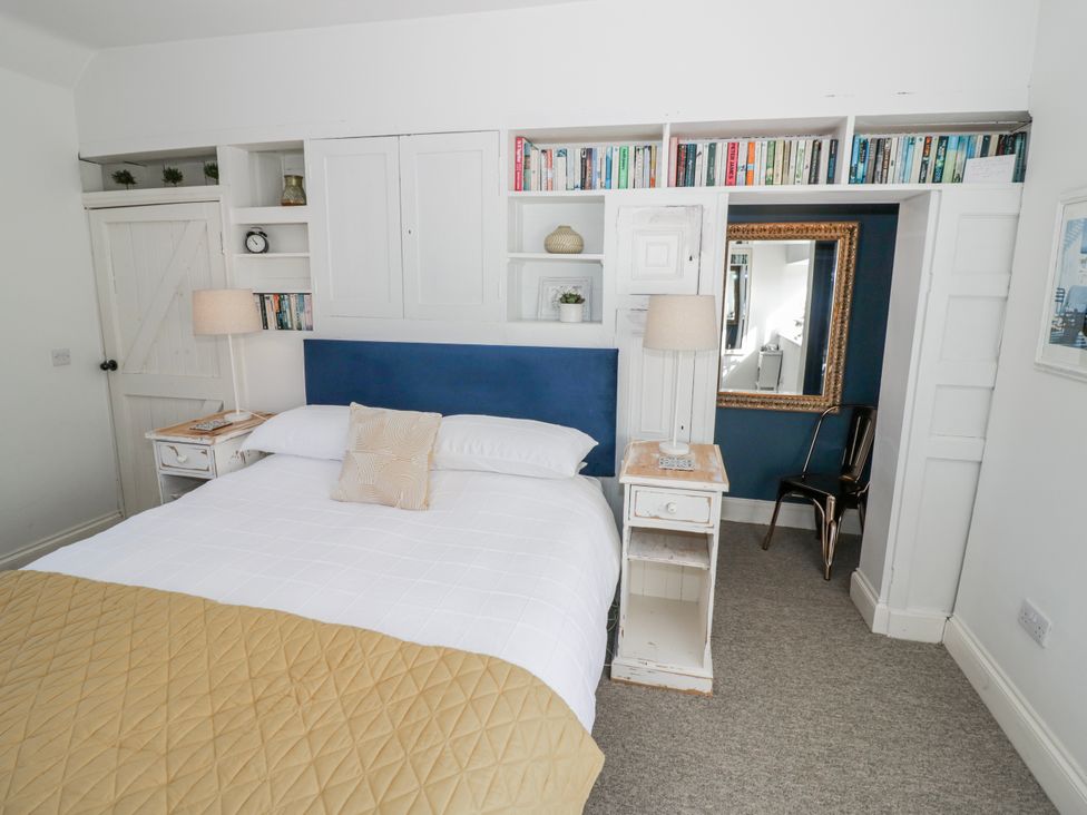 A bedroom with a bed and bookshelf at Halliday’s Cottages - The Folly Greetham near Cottesmore