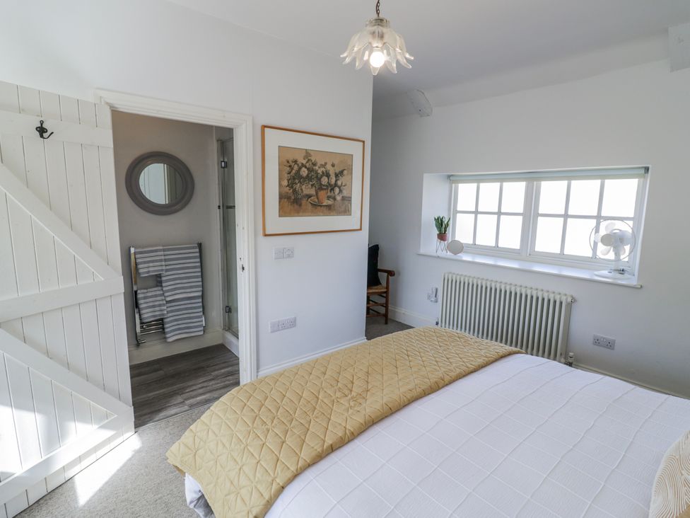 A bedroom with a bed and a mirror at Halliday’s Cottages - The Folly Greetham near Cottesmore