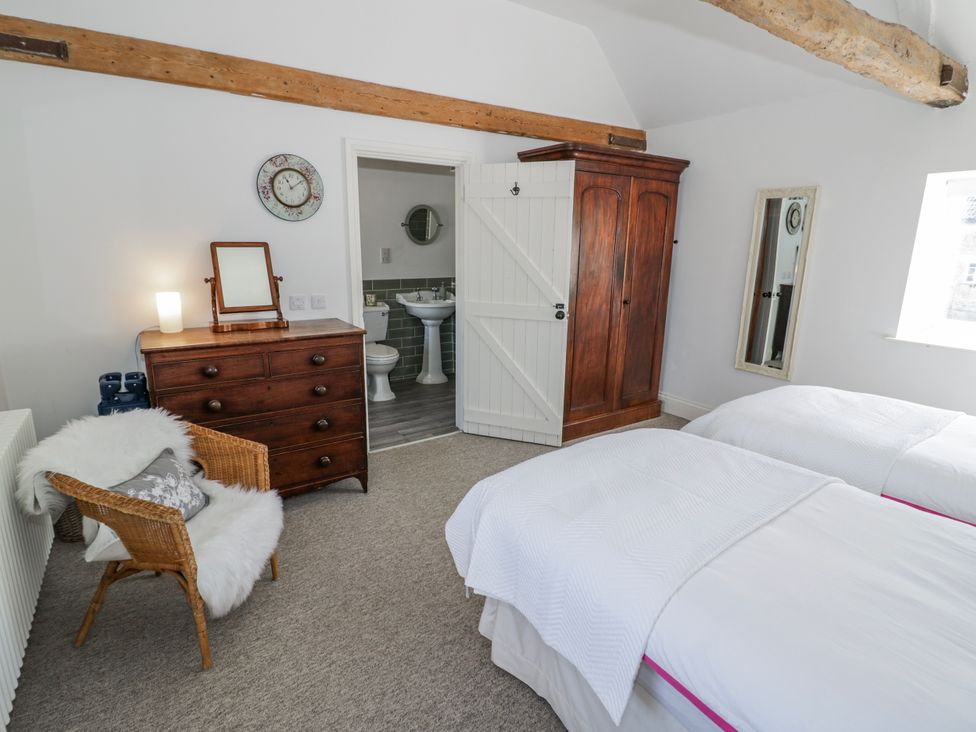 A bedroom with two beds and a dresser at Halliday’s Cottages - The Folly Greetham near Cottesmore