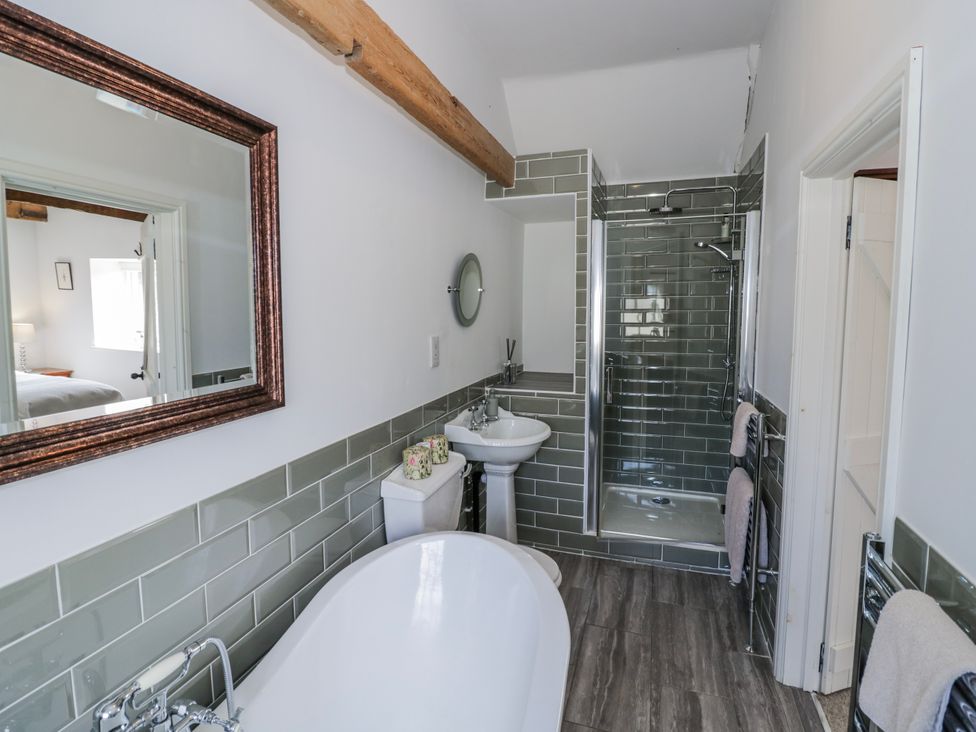 A bathroom with a bathtub, sink, shower, and mirror at Halliday’s Cottages - The Folly Greetham near Cottesmore
