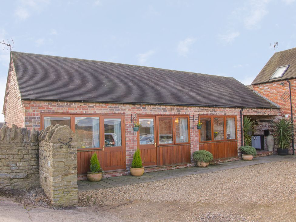A brick building with windows and a pathway at Herdwick Cottage in Much Wenlock