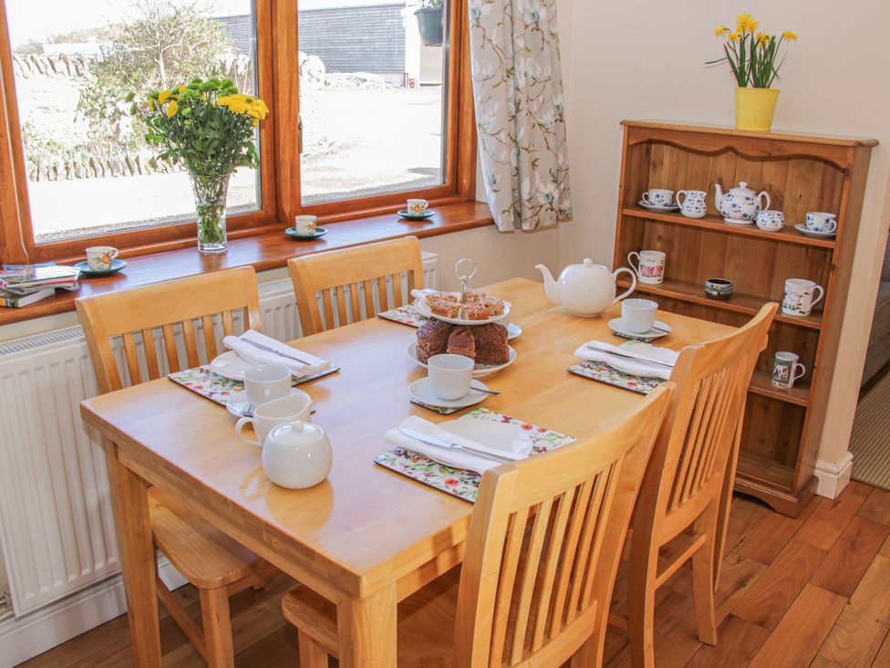 A dining room with a table set for tea and a floral arrangement at Herdwick Cottage Much Wenlock