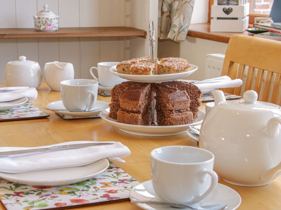A dining room table set with tea and cake at Herdwick Cottage in Much Wenlock