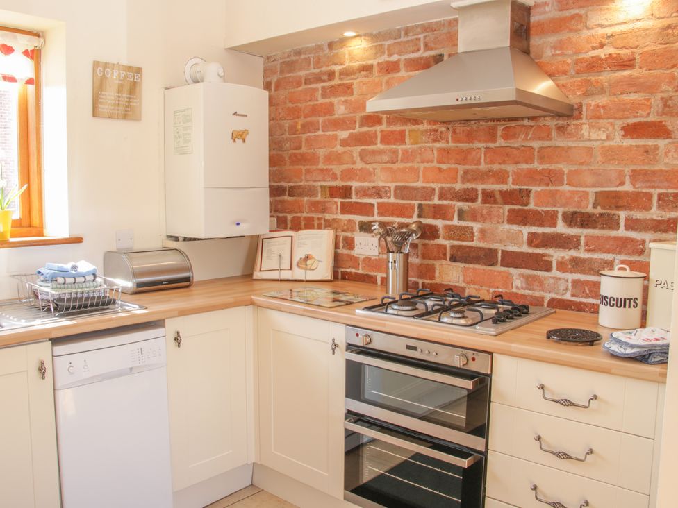 A kitchen with a gas stove and dishwasher at Herdwick Cottage Much Wenlock