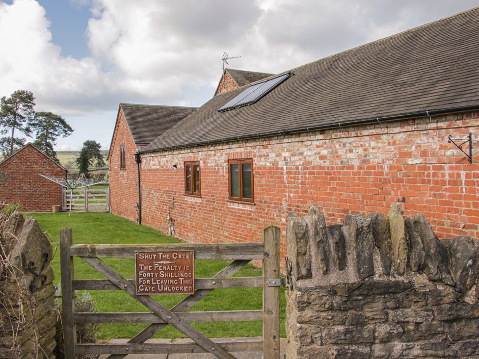 A gate and brick buildings in the yard at Herdwick Cottage in Much Wenlock