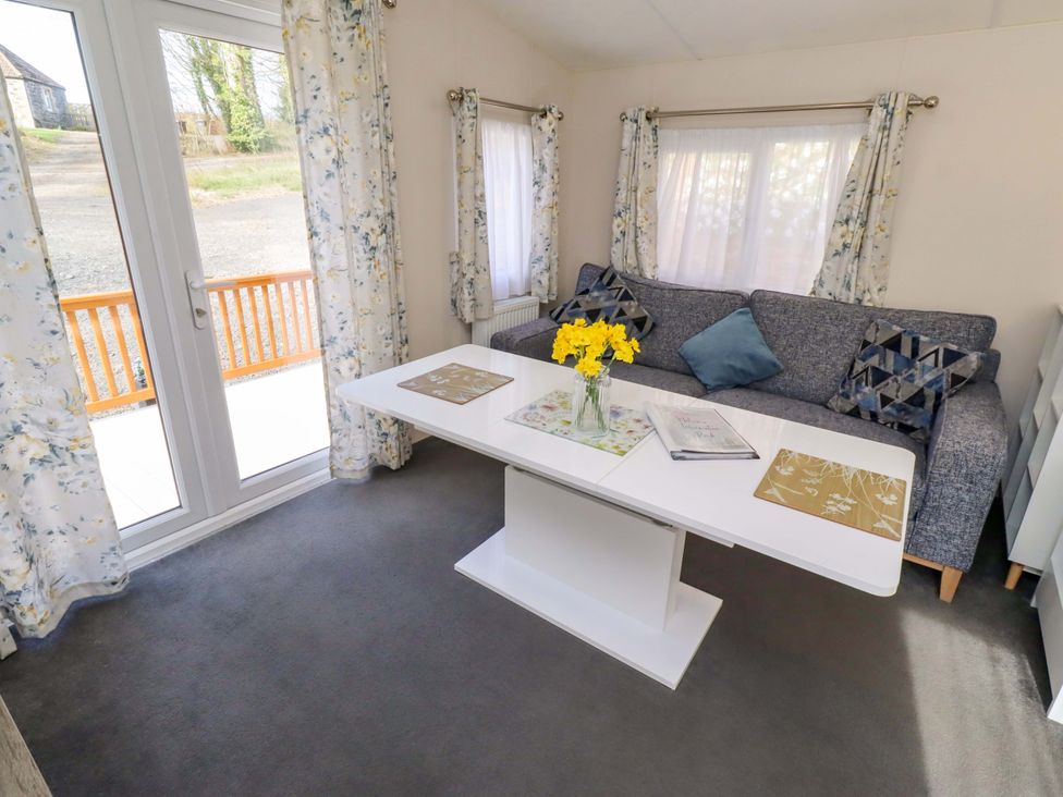 A living room with a sofa and table at Gardeners Lodge