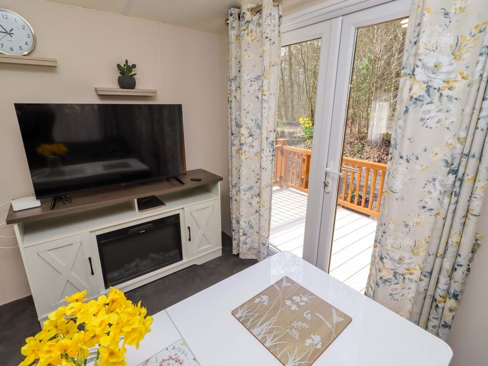 A living room with a television and a window at Gardeners Lodge
