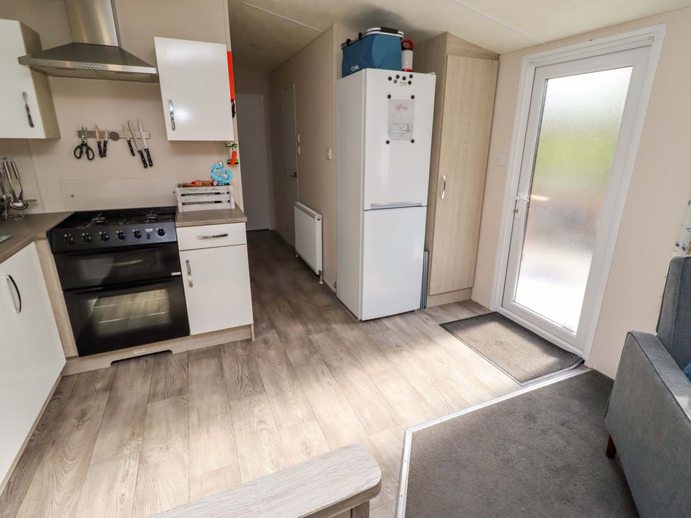 A kitchen with appliances and door to the outside at Gardeners Lodge