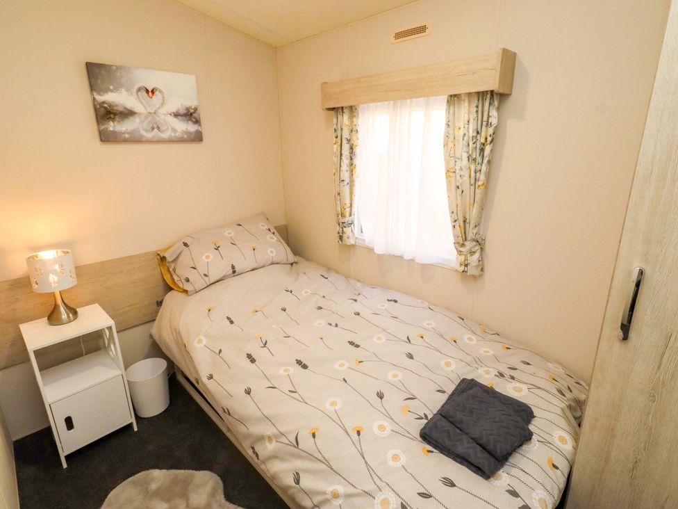 A bedroom with a bed and bedside table at Gardeners Lodge 