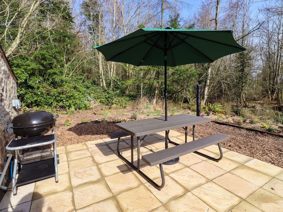 A picnic table with an umbrella and grill at Gardeners Lodge