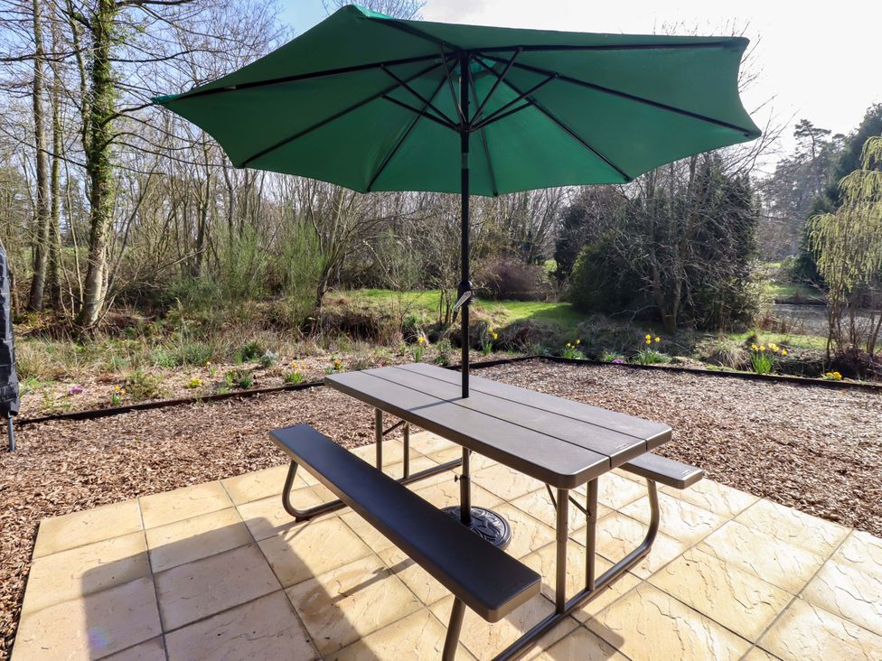 A garden with a table and umbrella at Gardeners Lodge 