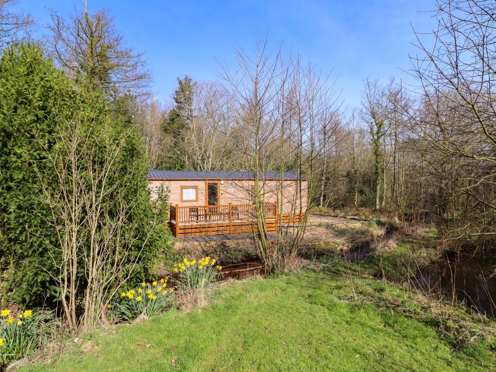 A cabin with a wooden deck in an outdoor area at Gardeners Lodge