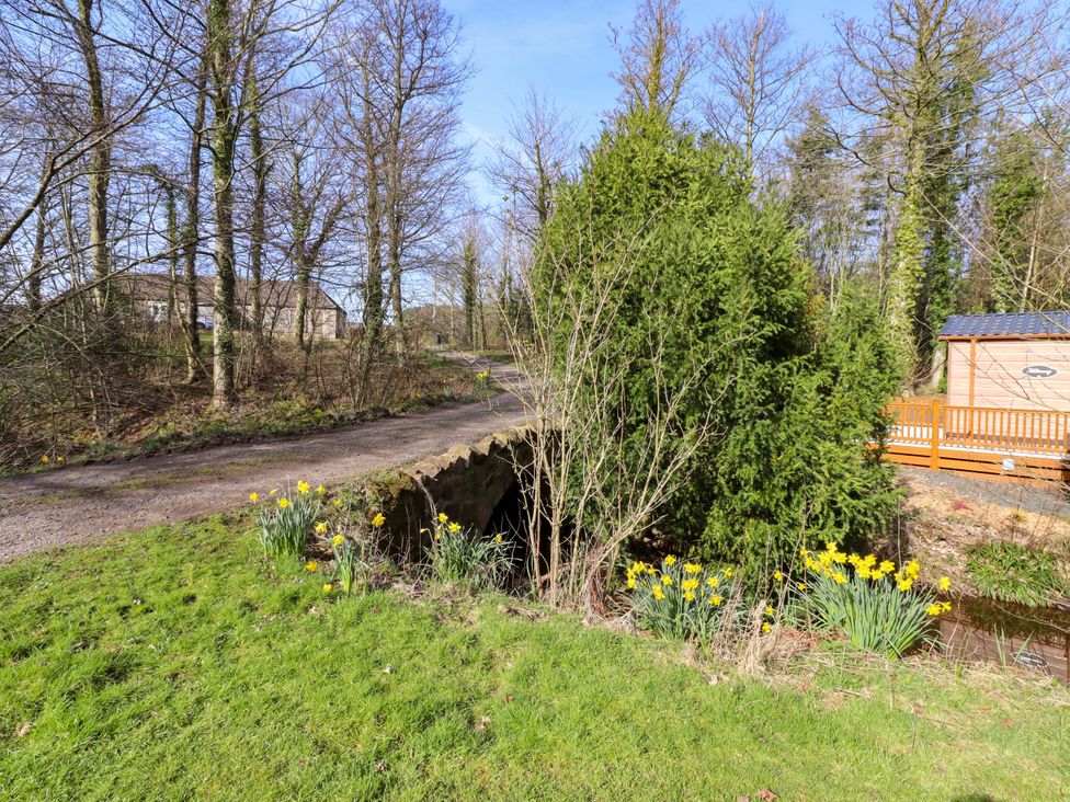 An outdoor scene with trees, flowers, and a cabin at Gardeners Lodge