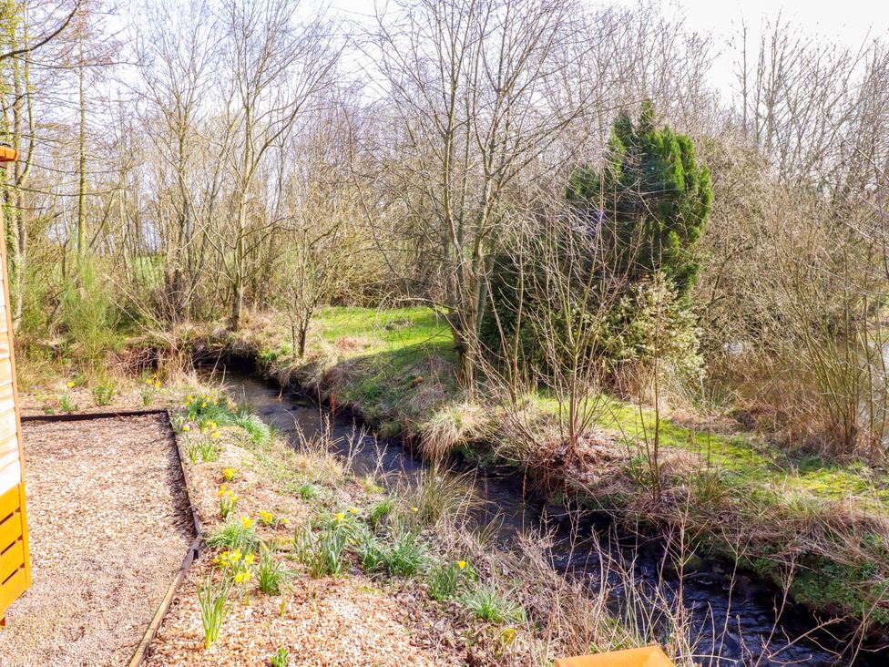 A garden with a stream and trees at Gardeners Lodge