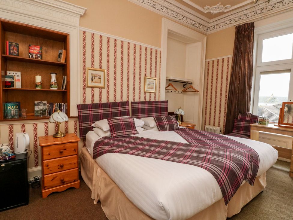 A bedroom with a bed, bookshelf, and window at Seaview Wellness Retreat in Carnoustie