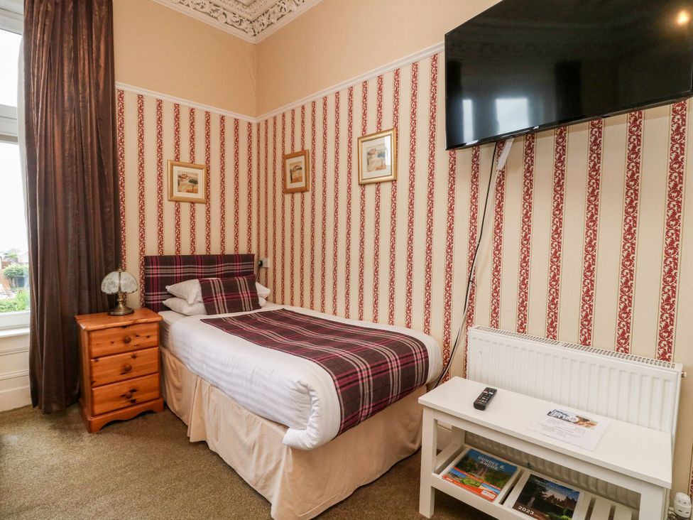 A bedroom with a bed, nightstand, and television at Seaview Wellness Retreat Carnoustie