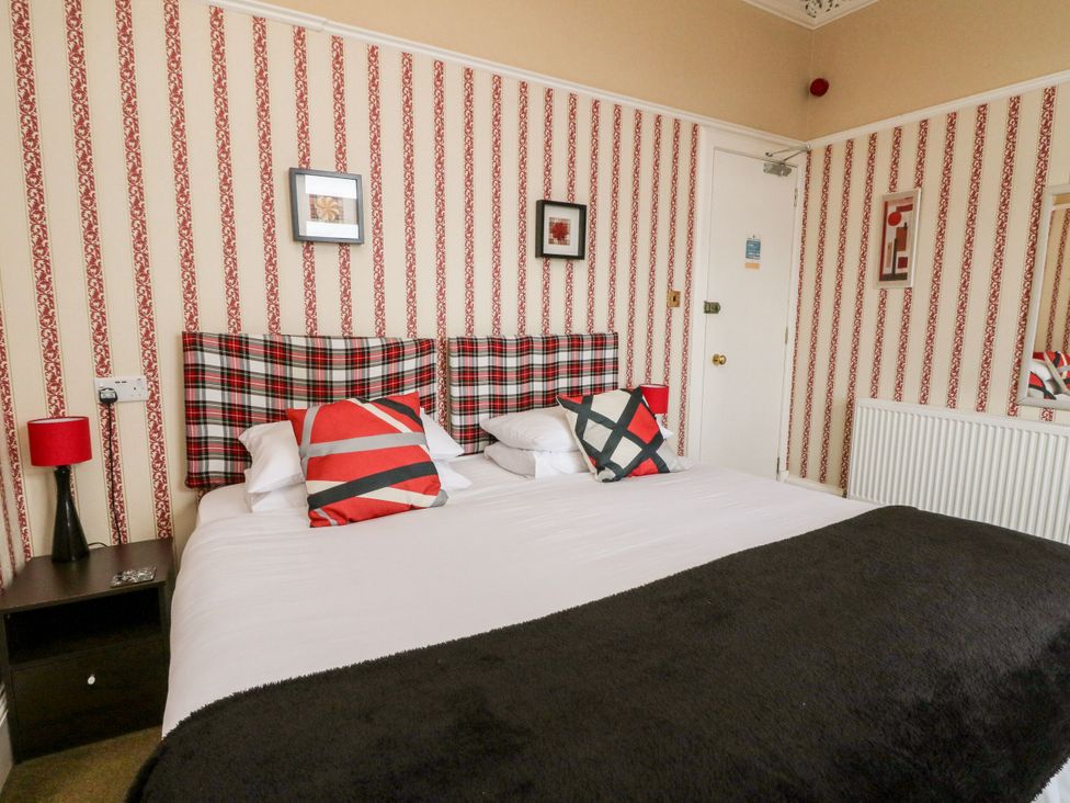 A bedroom with a bed, lamps, and artwork at Seaview Wellness Retreat in Carnoustie