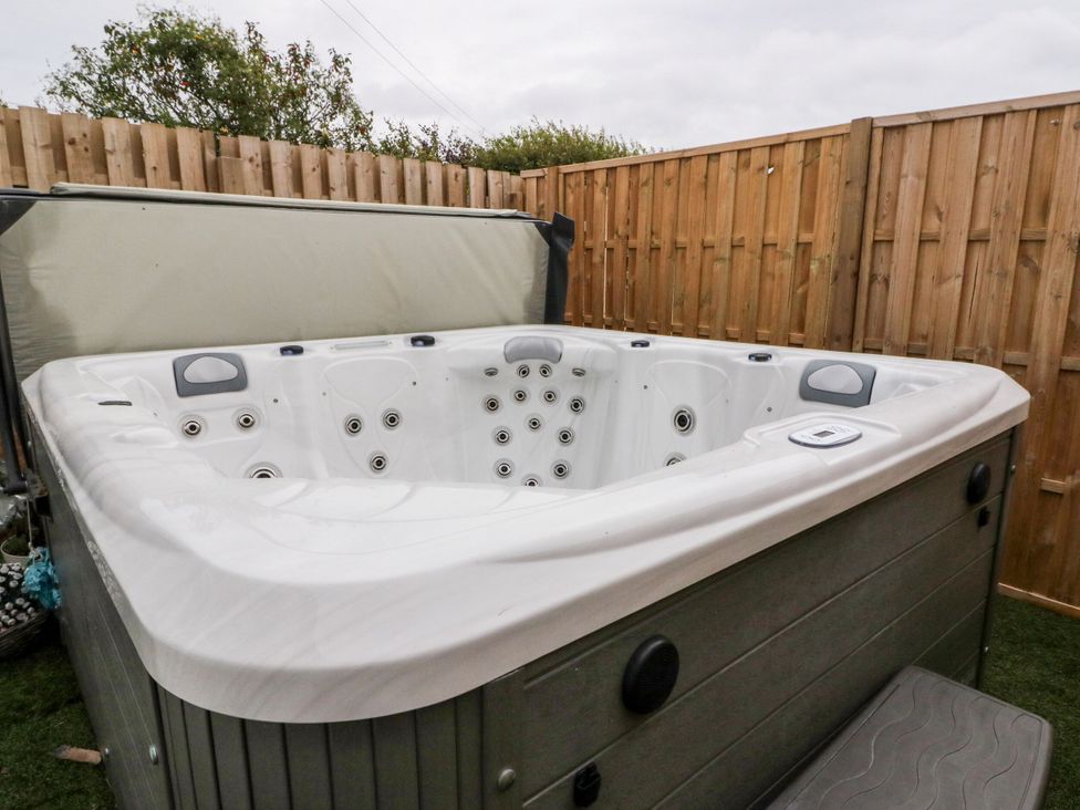 A hot tub with a cover and steps in a garden at Seaview Wellness Retreat in Carnoustie