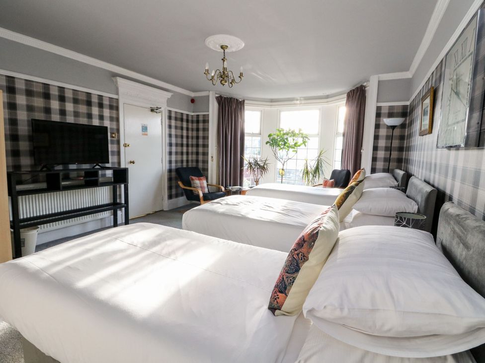 A bedroom with three beds and a television at Seaview Wellness Retreat in Carnoustie