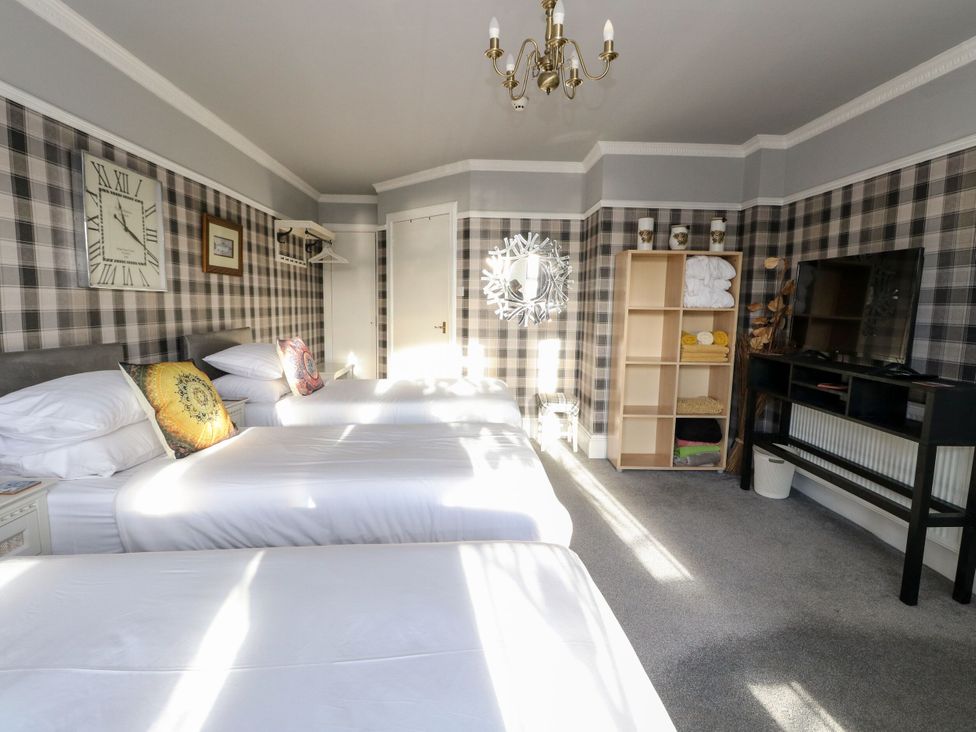A bedroom with three beds and a television at Seaview Wellness Retreat Carnoustie