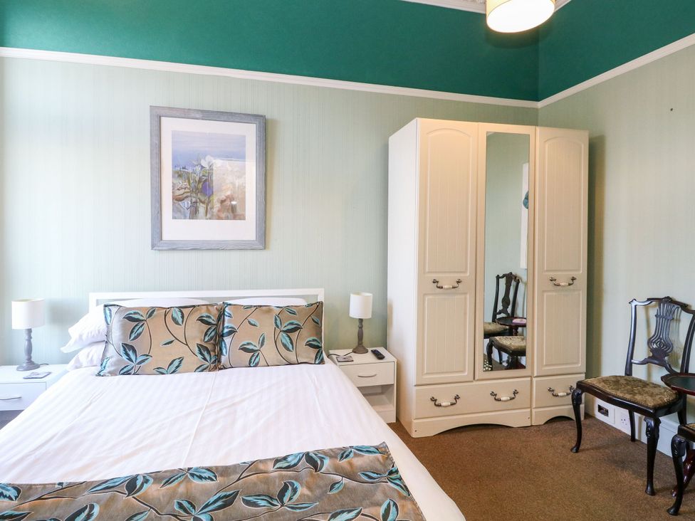A bedroom with a bed, wardrobe and chair at Seaview Wellness Retreat in Carnoustie