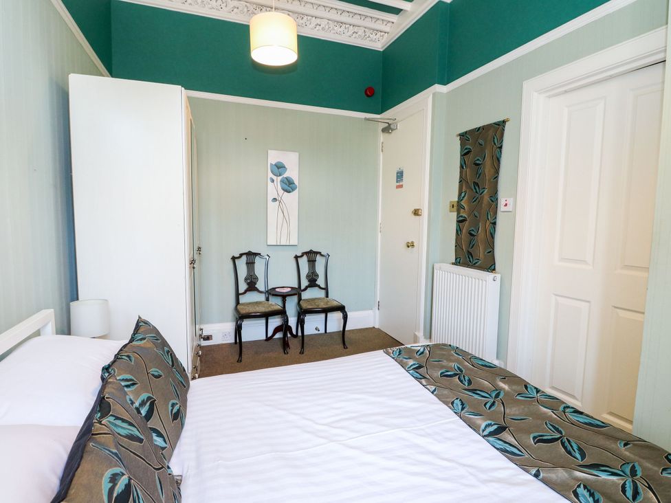 A bedroom with a bed and chairs at Seaview Wellness Retreat in Carnoustie