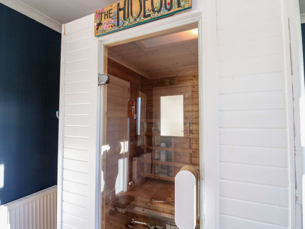 A sauna entry with a wooden wall and glass door at Seaview Wellness Retreat in Carnoustie