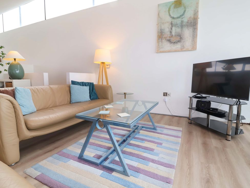 A living room with a sofa, coffee table, and television at 12 Nautilus, Westward Ho!