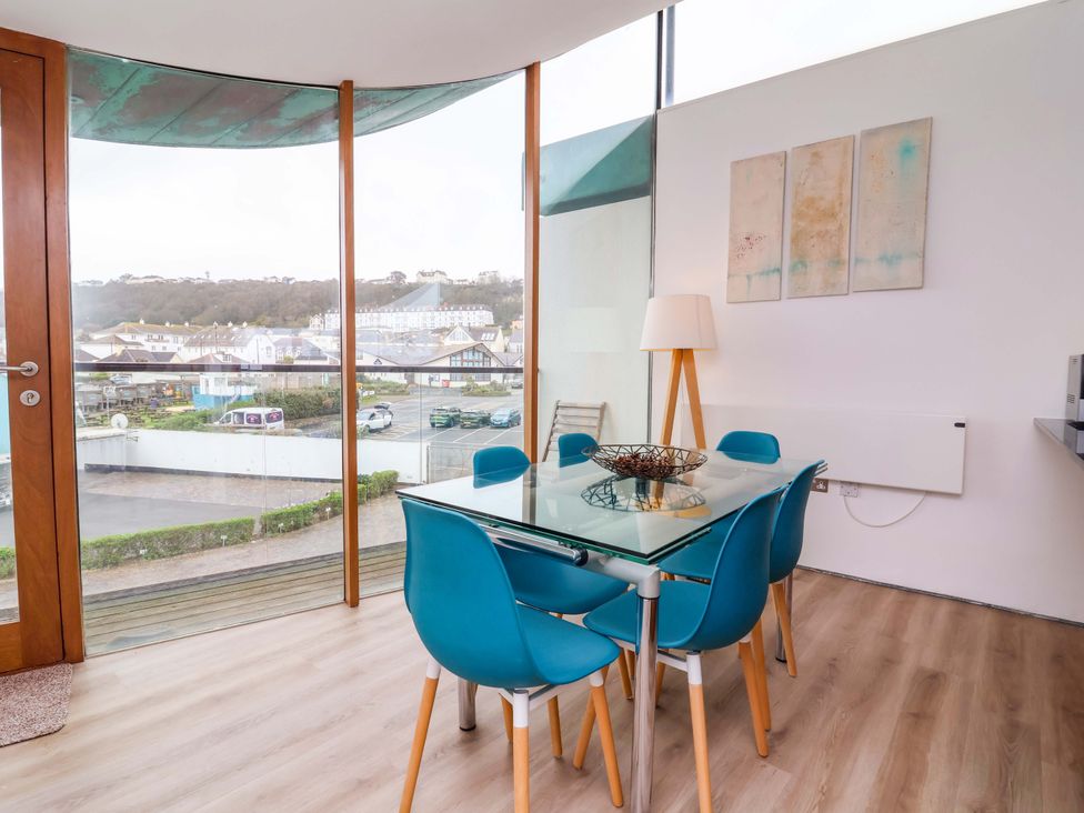 A dining room with a glass table and blue chairs at 12 Nautilus in Westward Ho!