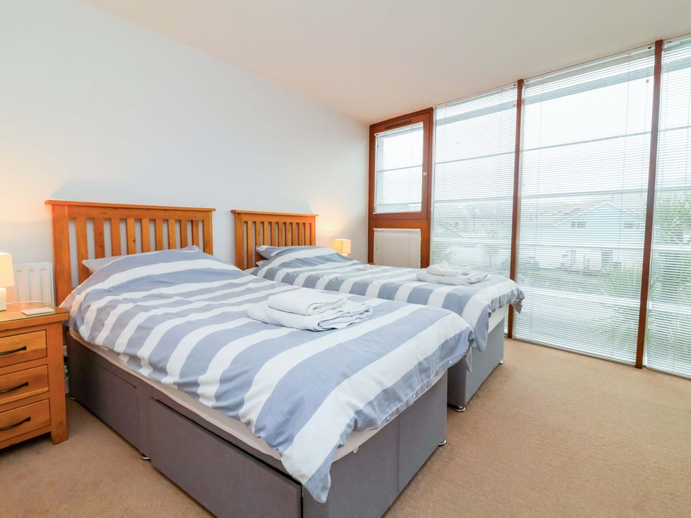 A bedroom with two beds and a bedside table at 12 Nautilus in Westward Ho!