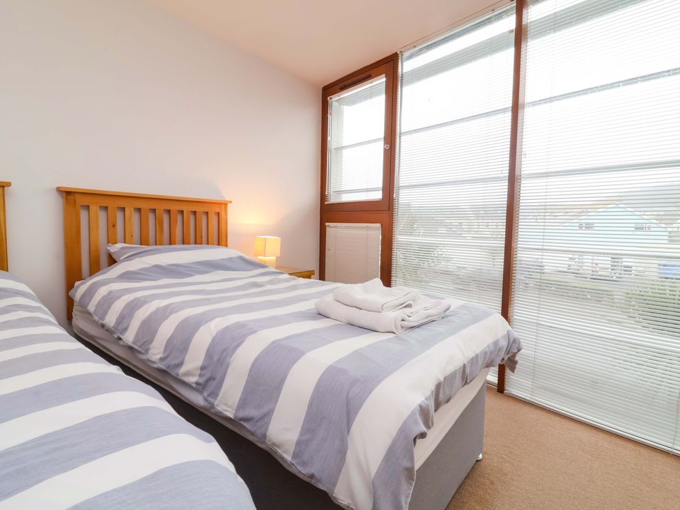 A bedroom with two beds and a bedside lamp at 12 Nautilus in Westward Ho!