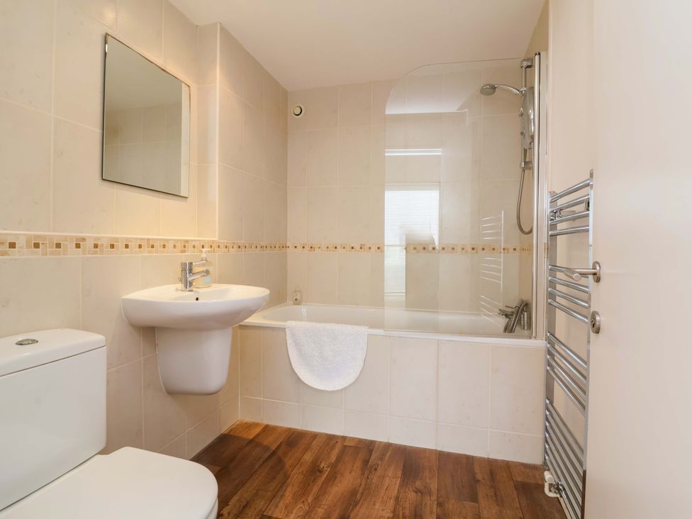 A bathroom with a sink and shower over the bathtub at 12 Nautilus Westward Ho!