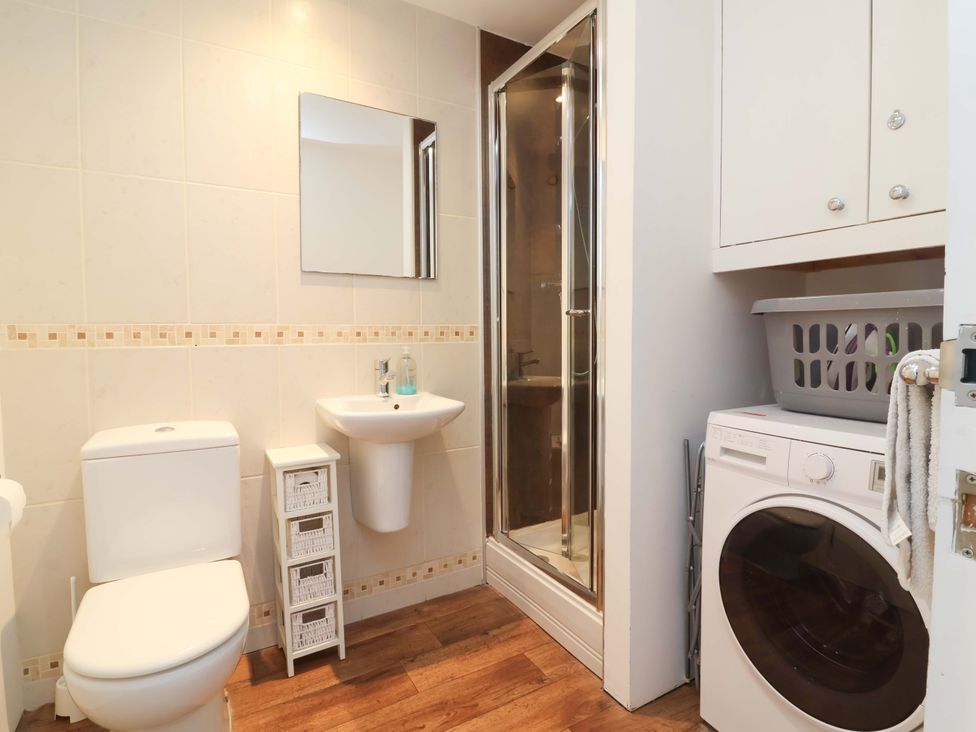 A bathroom with a shower, sink, and washing machine at 12 Nautilus Westward Ho!