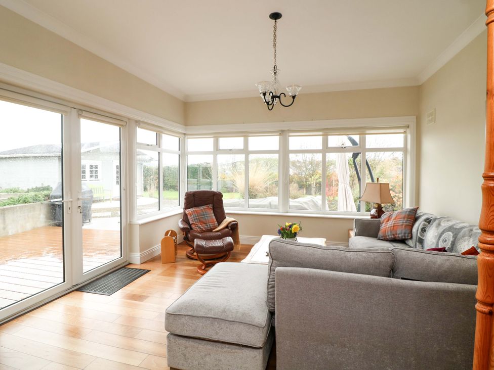 A conservatory with a sofa and armchair at Sunnyside in River Chapel