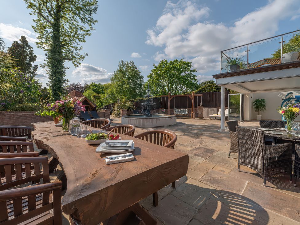 A garden with a wooden dining table and water fountain at Hamble House Southampton