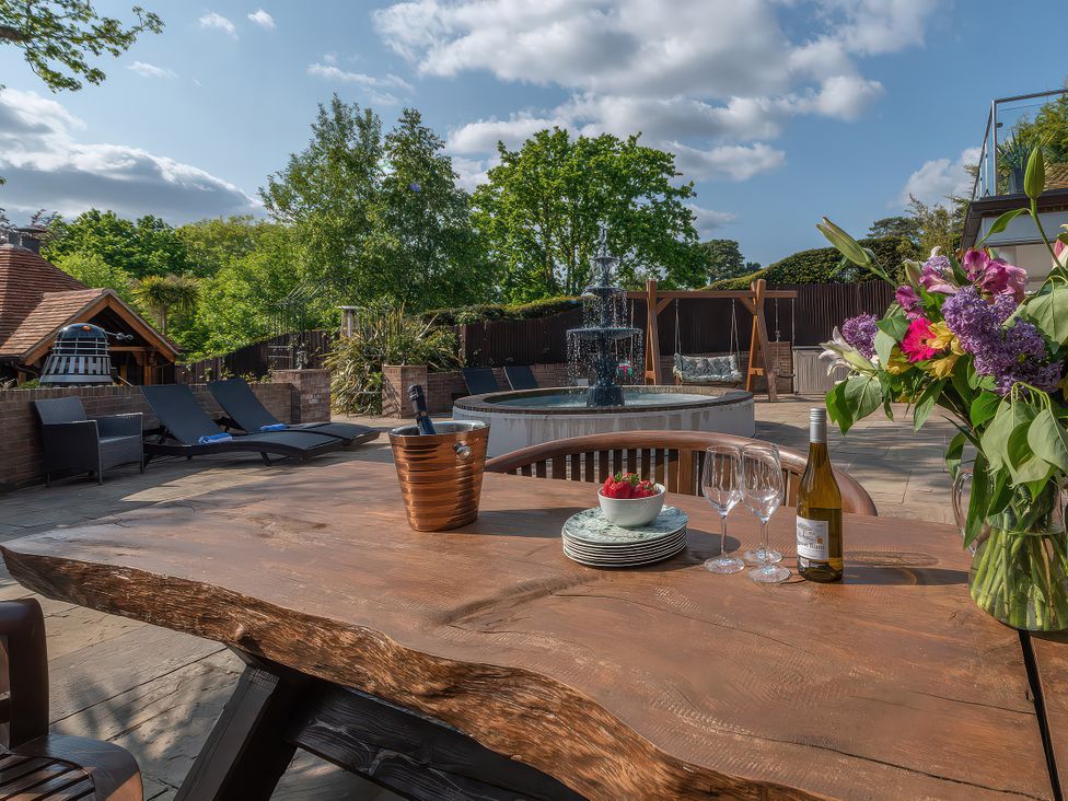An outdoor area with a wooden table, fountain, and lounge chairs at Hamble House in Southampton