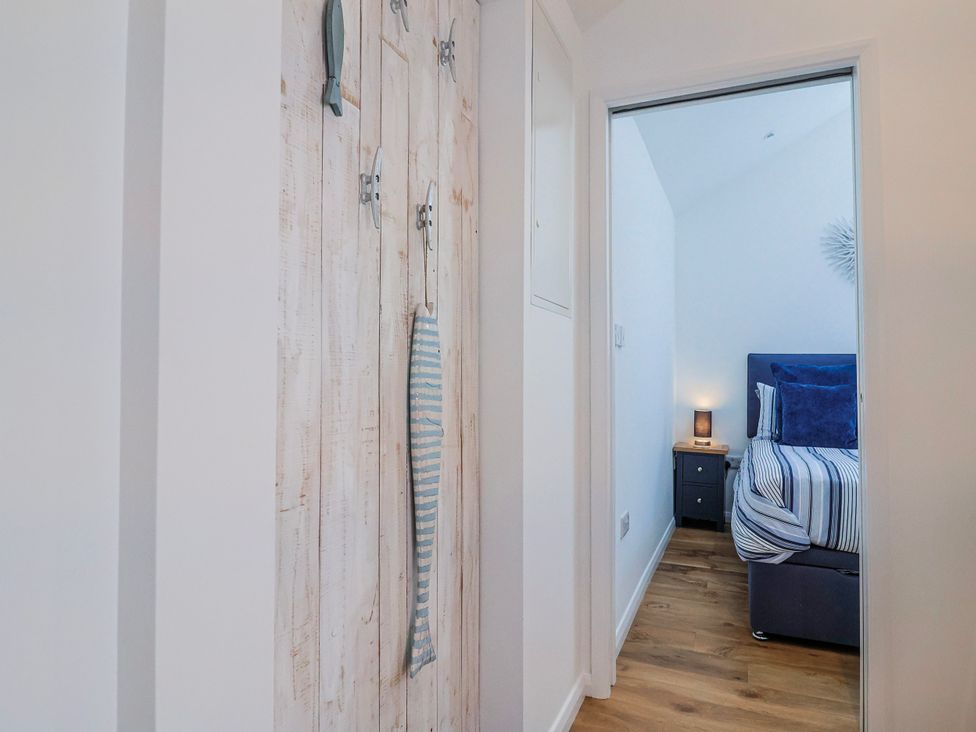 A hallway leading to a bedroom with a bed and bedside table at Le Petit Glen in Uplyme