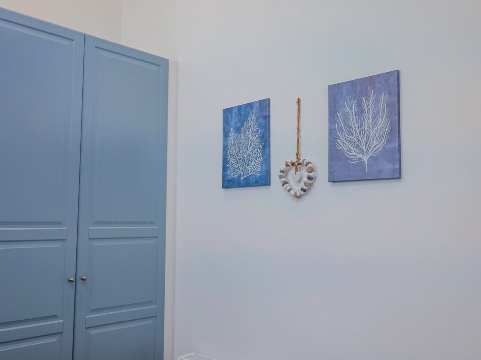 A room with a wardrobe and wall art at Le Petit Glen in Uplyme